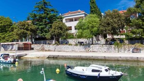 A marina with boats docked, a stone wall, and a building with a red roof. - Holiday apartment with air conditioning and sea view (Crikvenica)