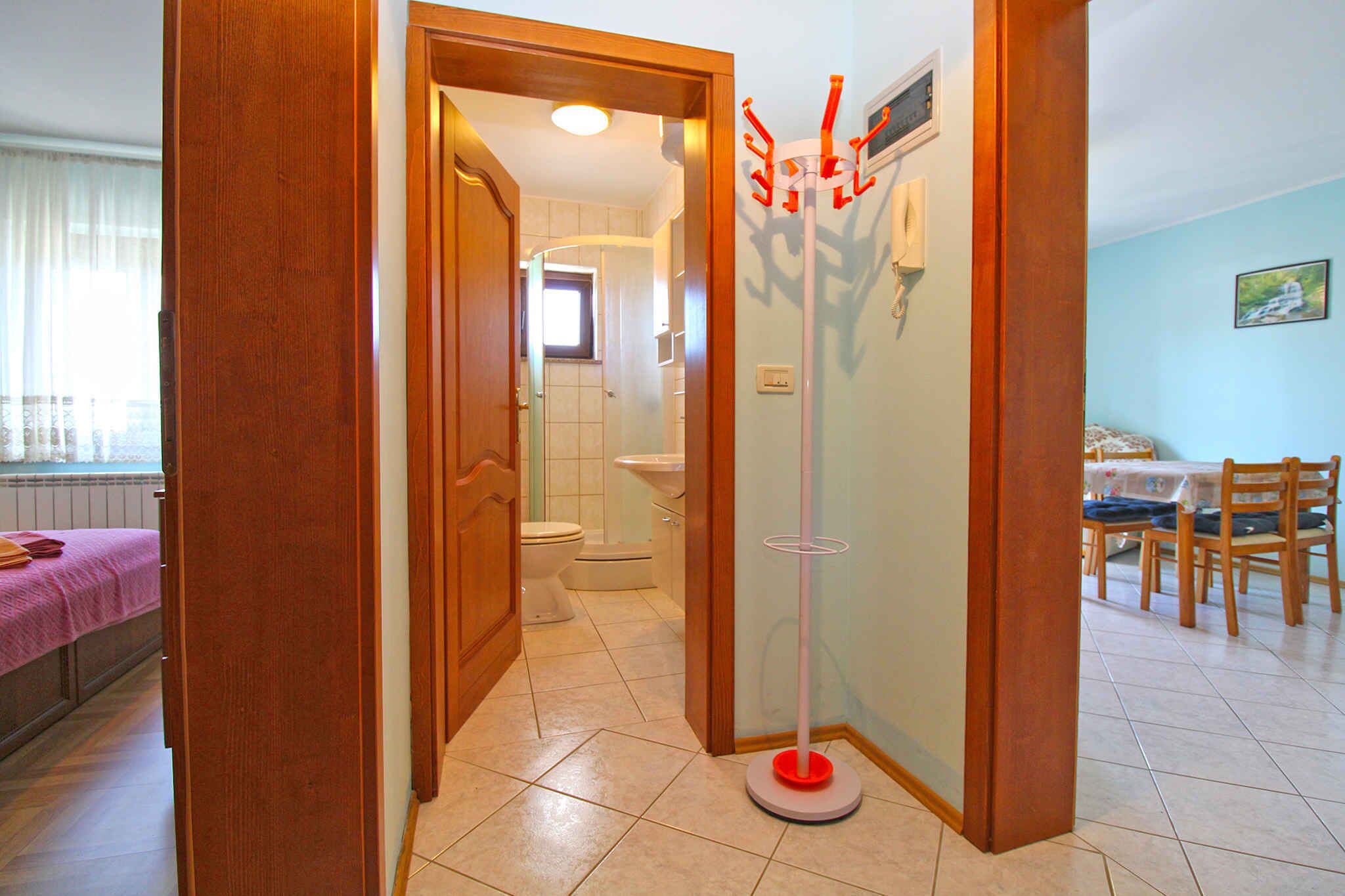 A bathroom with a toilet, sink, and shower. There is a wooden door leading to another room.