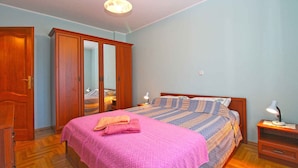 Une chambre à coucher avec un lit, une armoire en bois et une table de chevet avec une lampe.