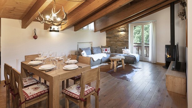 A cozy, rustic interior with a wooden dining table set for a meal, a comfortable sofa, and a fireplace. - Charme Mountain Maison (Temu)