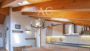 A rustic kitchen with wooden cabinets, a central island, and a chandelier. - Charme Mountain Maison (Temu)