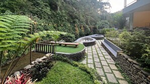 Ein Garten mit einem Kiesweg, Sitzbereichen und üppiger Bepflanzung.