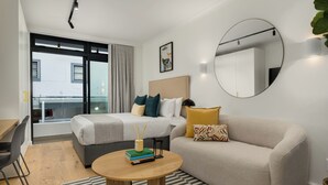 Ein modernes Hotelzimmer mit Bett, einer Sitzecke, einem Schreibtisch und einem runden Tisch.