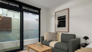 A modern living room with a sofa, a coffee table, and a framed picture on the wall. - The Sage | Studio With Courtyard Access (Cape Town)