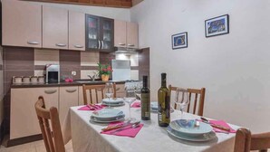 A dining area with a table set for four, a kitchen in the background, and two framed pictures on the wall. - Holiday home with air conditioning (Pula)