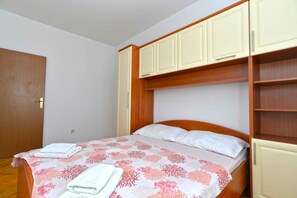 A bedroom with a bed, a wooden headboard, a wardrobe, and a door. - Holiday apartment with balcony and barbecue (Rovinj)