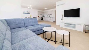 A modern living room with a sectional sofa, two round tables, and a flat-screen TV mounted on the wall. - Holiday apartment fully air-conditioned with balcony and sea view (Dramalj)