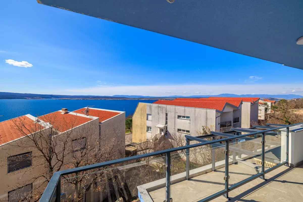 A balcony with a clear view of the sea and distant mountains.
