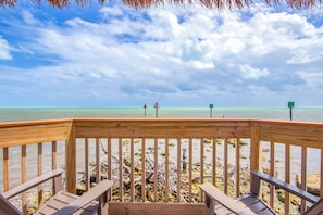 Een houten terras met uitzicht op zee en strand.