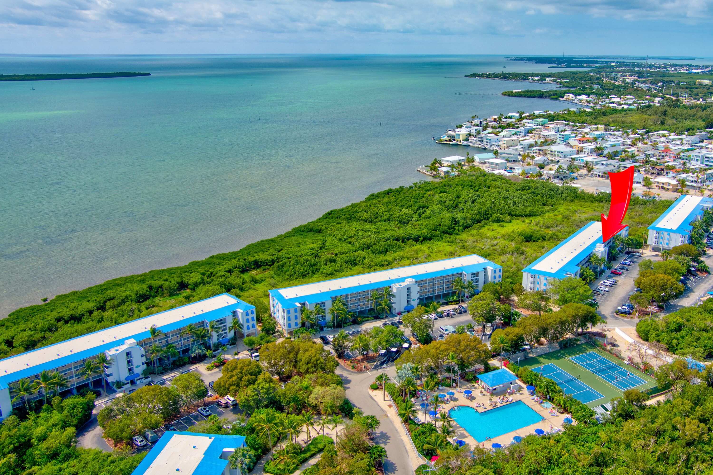 An aerial view of a resort with multiple buildings, a swimming pool, and a tennis court.