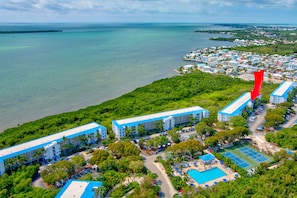 Een luchtbeeld van een resort met meerdere gebouwen, een zwembad en een tennisbaan.