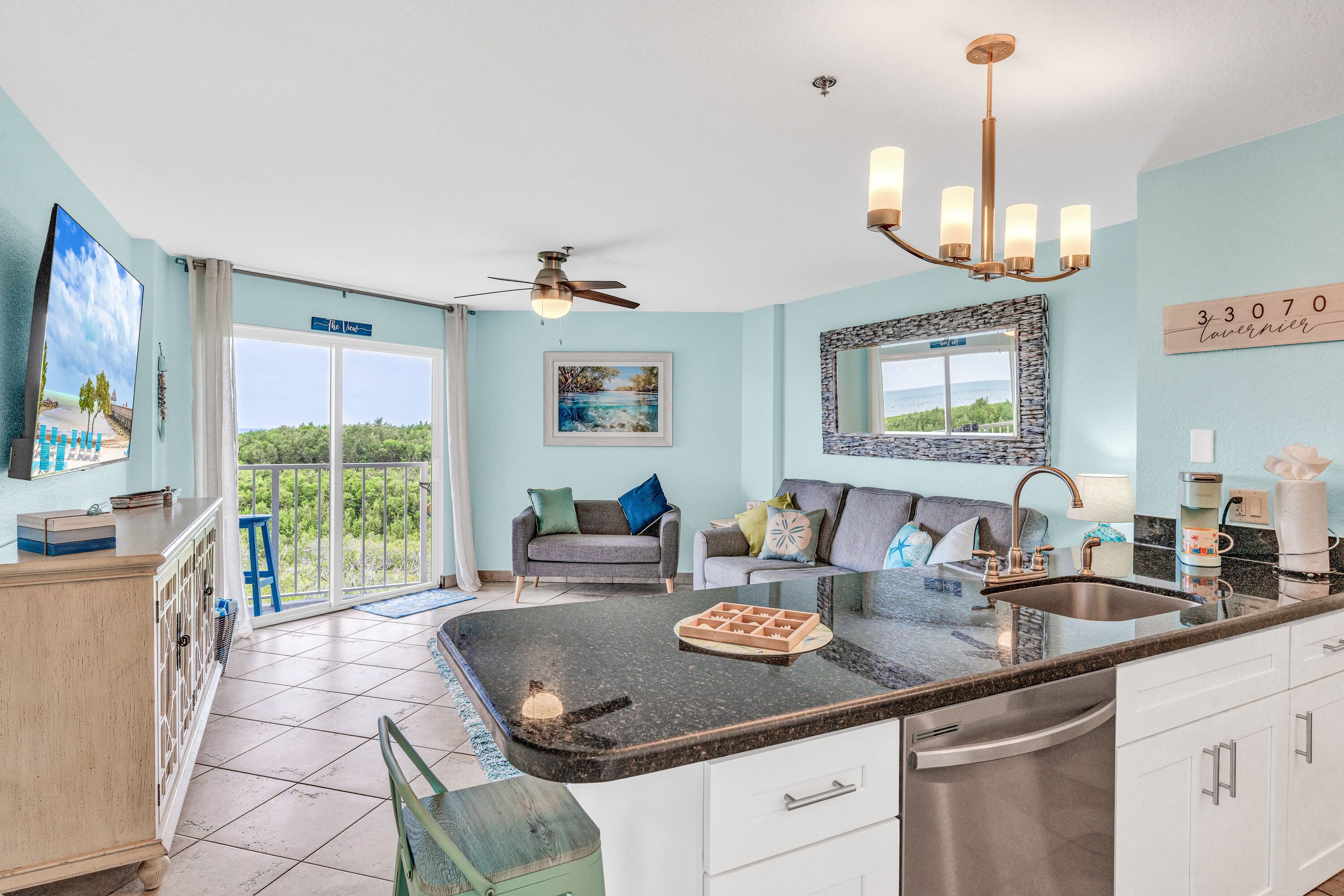 A modern kitchen with a large island, a dining area with a sofa, and a view of the outdoors.