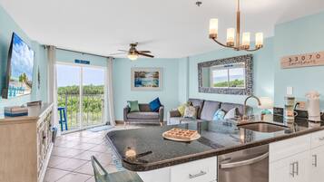 A modern kitchen with a large island, a dining area with a sofa, and a view of the outdoors.