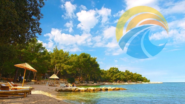 A beach with sun loungers, a gazebo, and a clear view of the sea.