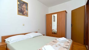 A bedroom with a bed, a nightstand, a wardrobe, and a painting on the wall.