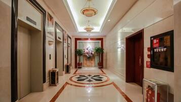 A hotel corridor with a polished floor, a central floral arrangement, and a modern light fixture.
