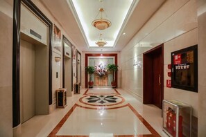 A hotel corridor with a polished floor, a central floral arrangement, and a modern light fixture. - Guilong Hotel (Guiyang)