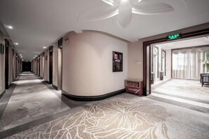 A hotel corridor with a carpeted floor, a reception desk, and a door marked 'EXIT'. - Guilong Hotel (Guiyang)
