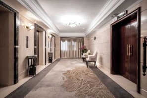 A hotel hallway with a carpet, a chandelier, a dining area, and a reception desk. - Guilong Hotel (Guiyang)