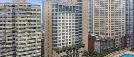 A high-rise building with multiple floors, a swimming pool, and surrounding greenery.
