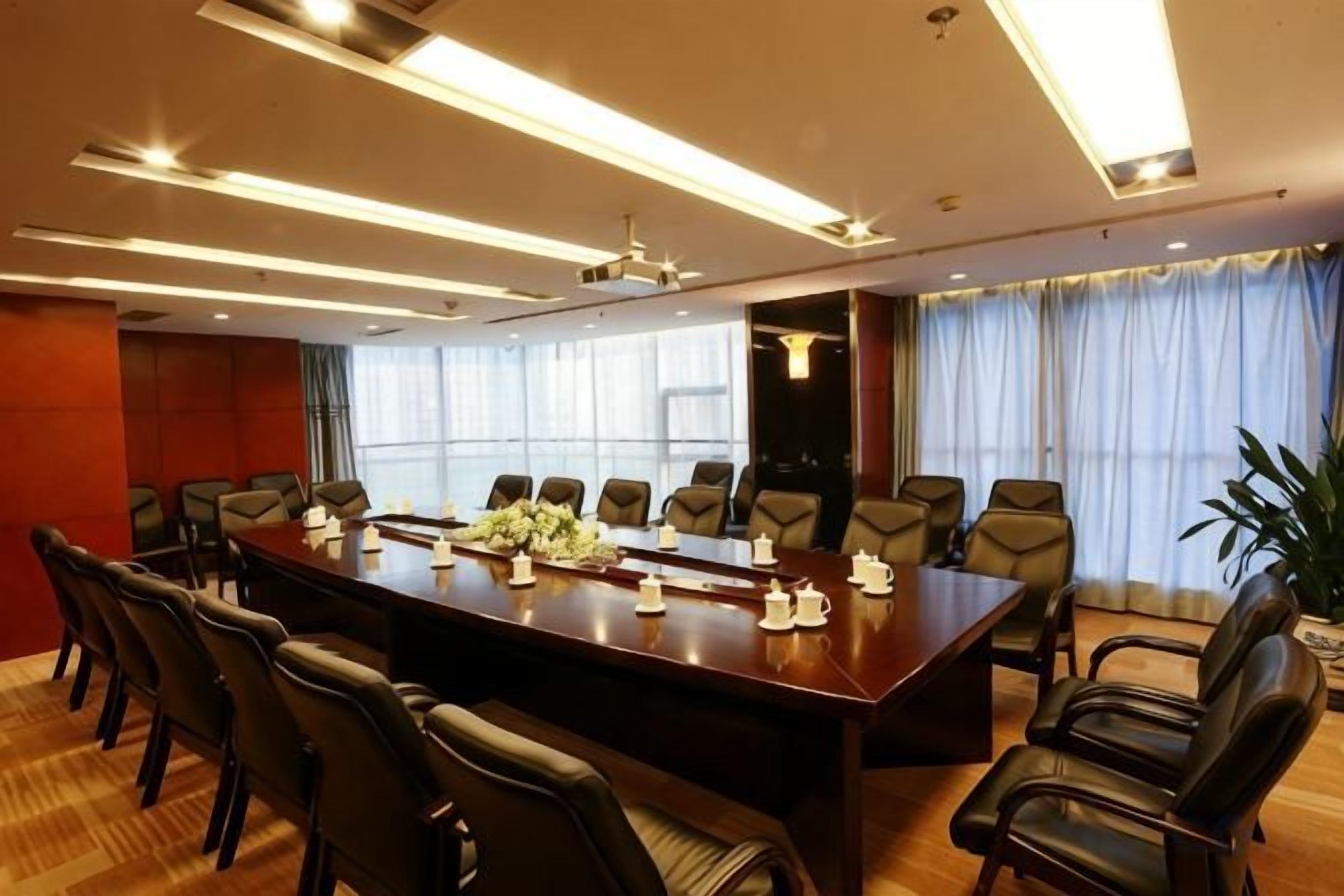 A conference room with a long table, multiple chairs, and a ceiling light fixture.