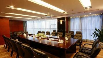 A conference room with a long table, multiple chairs, and a ceiling light fixture.