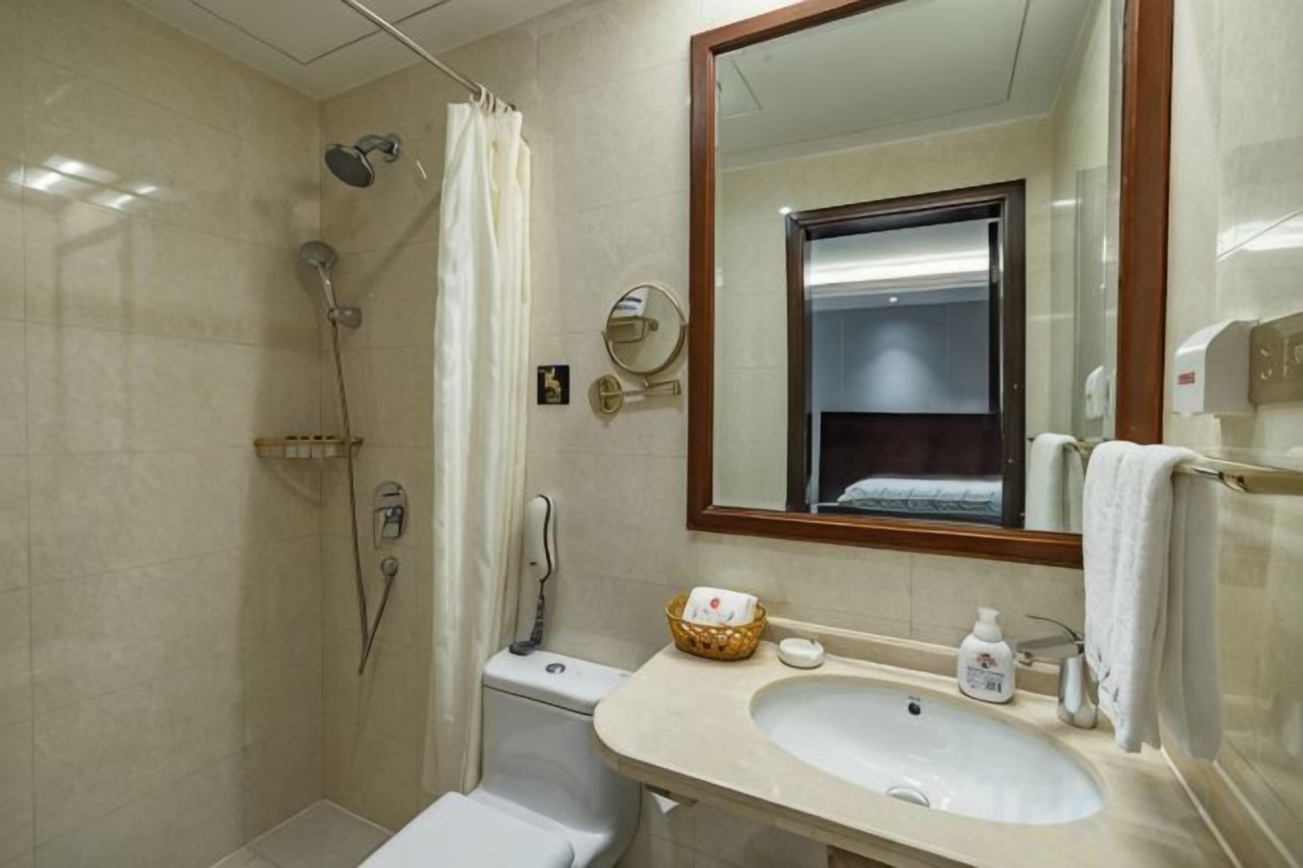 Un baño con ducha, inodoro, lavamanos y espejo.