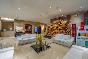 Un hall d’hôtel comprenant un comptoir d’accueil, deux canapés, une table basse et un grand mur décoratif.