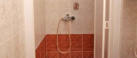 Een badkamer met een douche, toilet en wastafel.