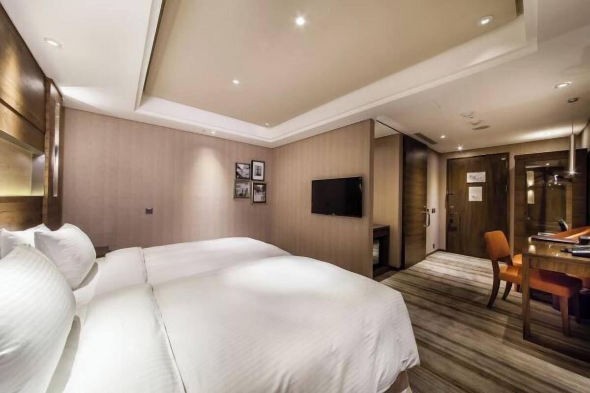 A hotel room with a large bed, a desk, and a television.
