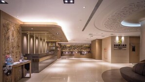 A modern hotel lobby with a reception desk, seating area, and a wall with a patterned design. - Green World Taipei Station (Taipei)