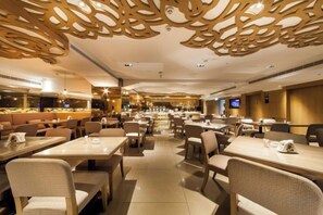 A restaurant with multiple dining tables and chairs, a bar area, and decorative ceiling panels. - Green World Taipei Station (Taipei)