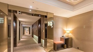 A modern hotel corridor with mirrored walls, a bench, and a wall-mounted lamp. - Green World Taipei Station (Taipei)
