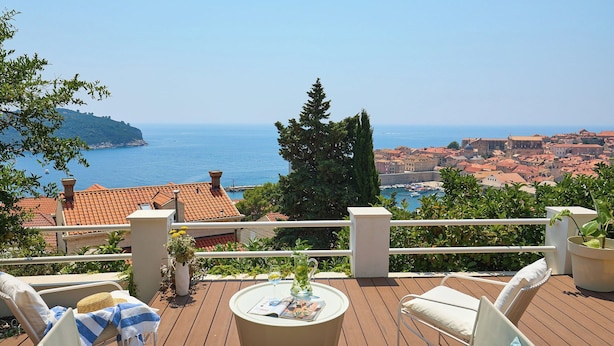 A deck with outdoor seating, a table with a pitcher and glass, and a view of the sea and city. - Hedera Estate, Hedera A8 (Dubrovnik)