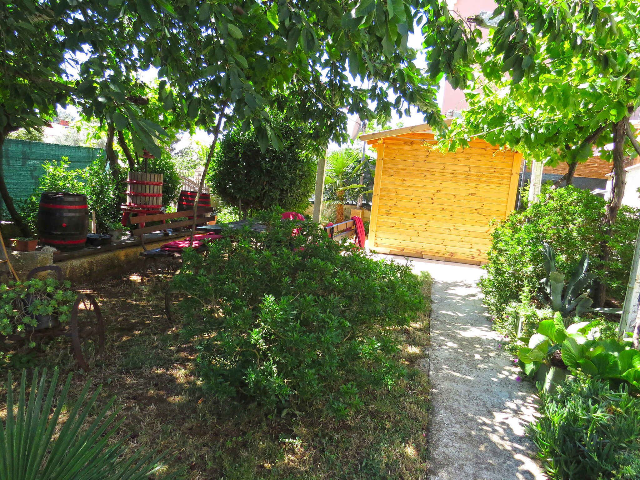 A garden with a wooden shed, a barbecue area, and various plants.