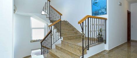 A staircase with a wooden handrail and metal balusters, leading to a landing with a window.