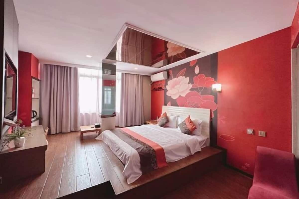 A modern hotel room with a large bed, a desk, and a view of the city.