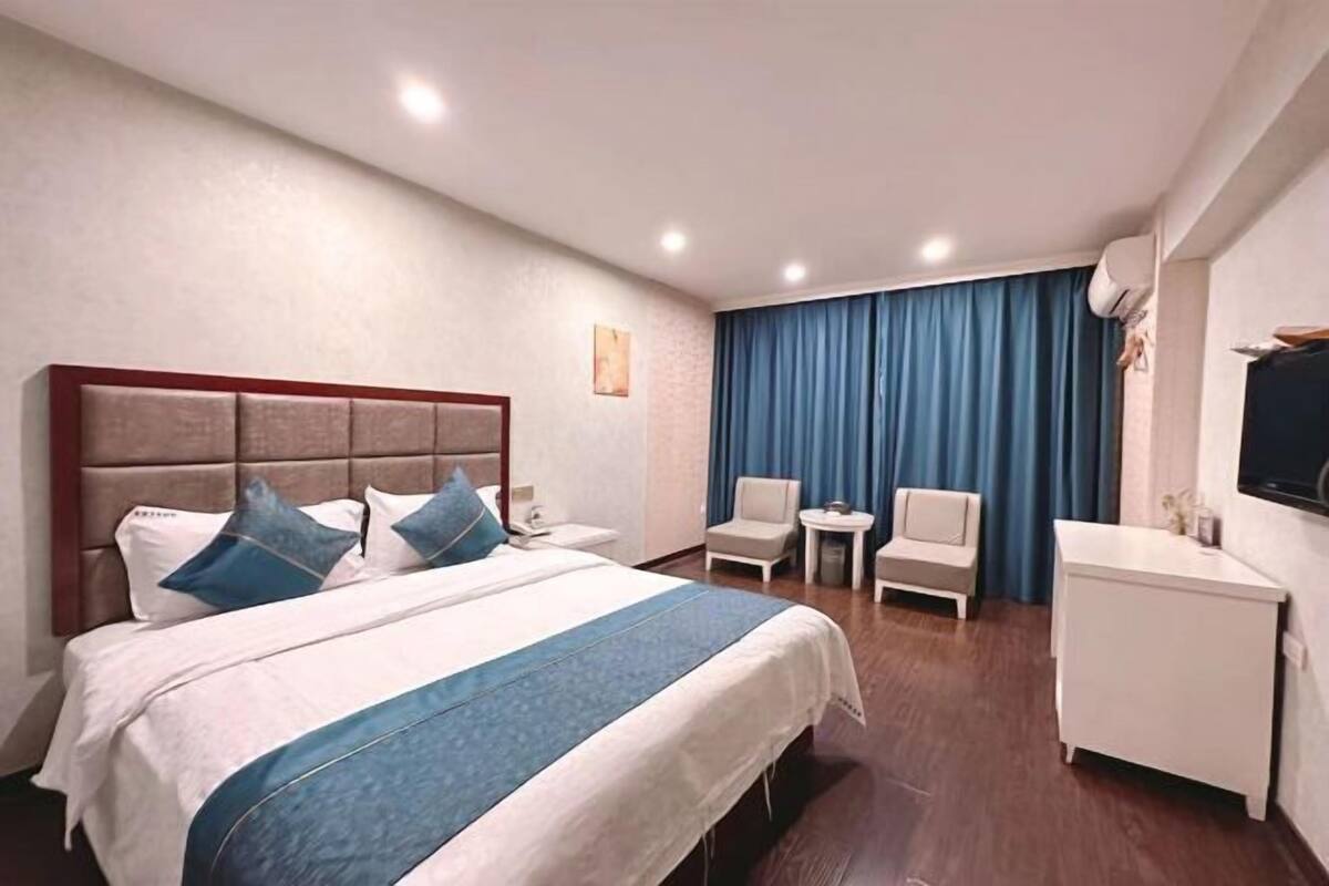 A hotel room with a bed, a desk, a chair, and a television.