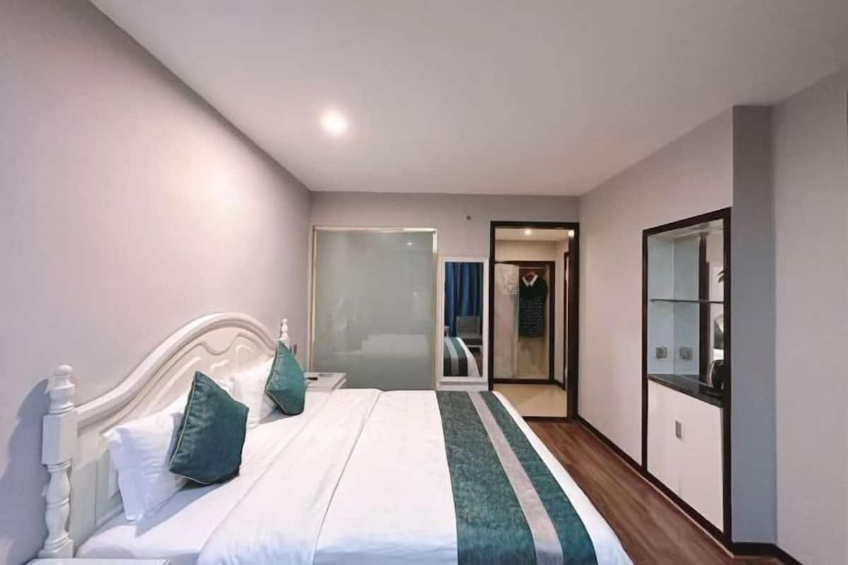 A bedroom with a bed, a nightstand, a glass shower enclosure, and a wardrobe.