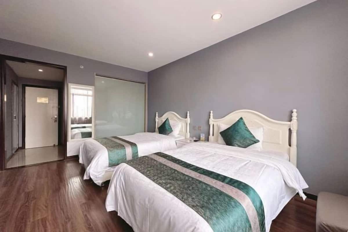 A hotel room with two beds, a large window, and a door leading to a balcony.