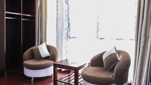 A room with two brown armchairs, a wooden table, and a large wardrobe. - Yiyoujia Express Hotel (Bengbu)