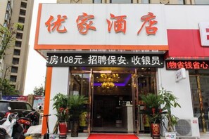 A hotel entrance with a red carpet, potted plants, and a sign indicating room rates and employment opportunities. - Bengbu Youjia Express Hotel (Greenland Century City) (Bengbu)