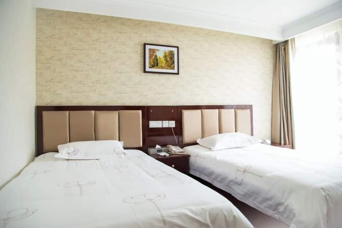 A hotel room with two beds, a headboard with a telephone, and a framed picture on the wall.