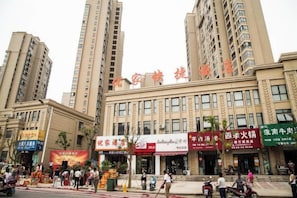 A multi-story building with commercial establishments on the ground floor, including a restaurant and a shop with a red sign. - Bengbu Youjia Express Hotel (Greenland Century City) (Bengbu)
