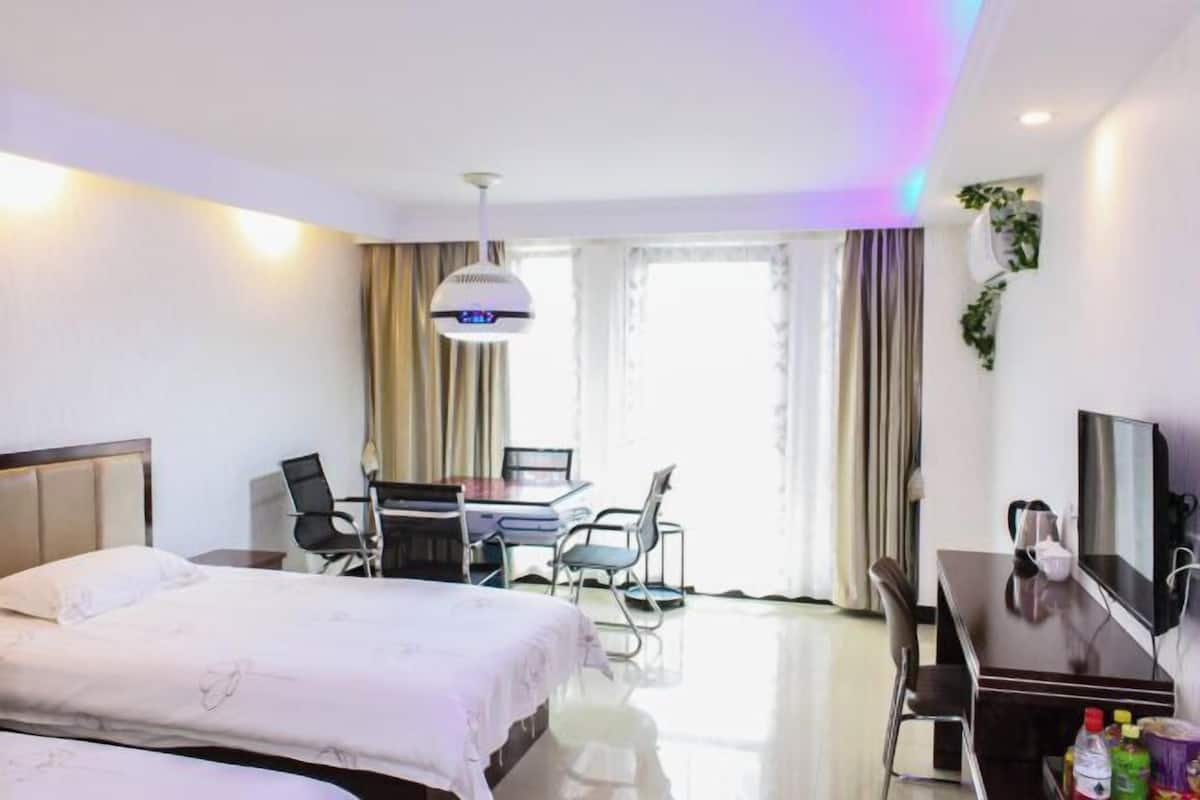 A hotel room with a bed, desk, chairs, and a TV.