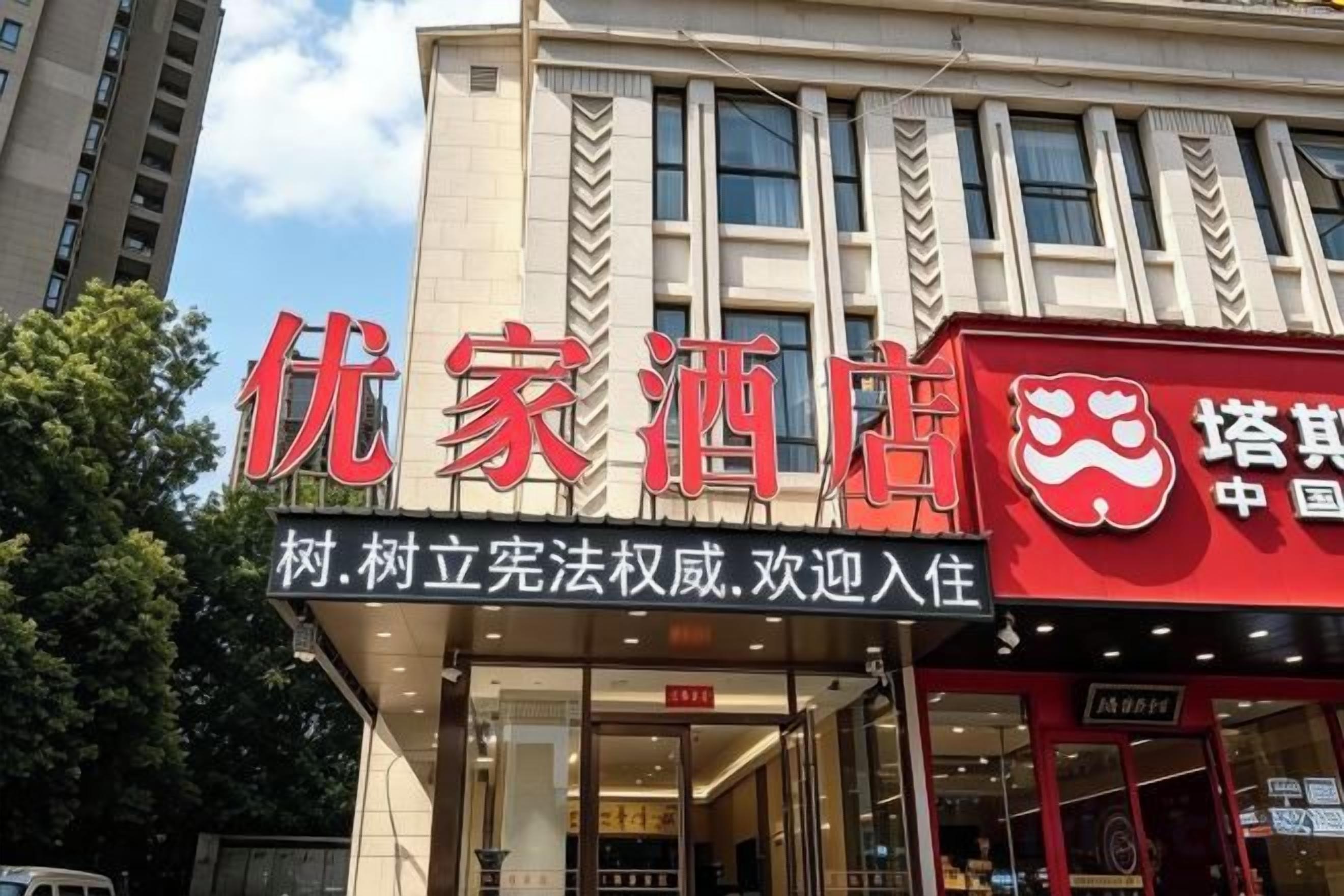 Un bâtiment sur lequel est apposée une enseigne indiquant « 优家酒店 », ce qui signifie qu’il s’agit d’un hôtel.