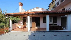 Une maison avec un toit en tuiles, un balcon avec une table et des chaises, et une antenne parabolique.