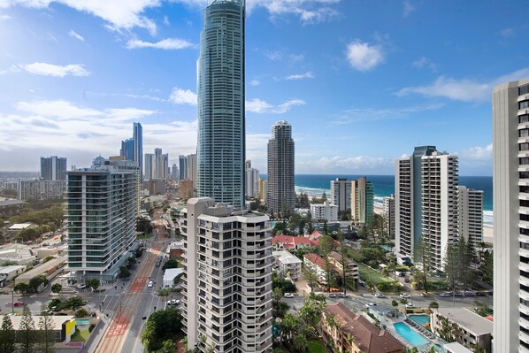 A high-rise building with a modern design, surrounded by other high-rise buildings and a clear view of the ocean.