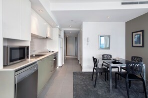 A modern kitchen with stainless steel appliances, a dining area with a table and chairs, and a view through a window.