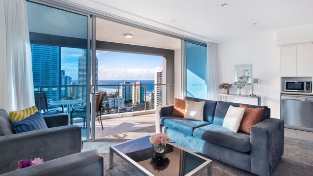 A modern living room with a balcony, a sofa set, a coffee table, and a kitchen area with a microwave.